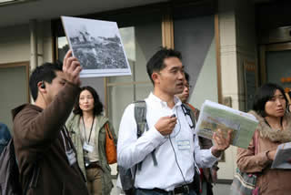 昭和20年4月の空襲直後の写真を手に説明 昭和20年4月の空襲直後の写真を手に説明